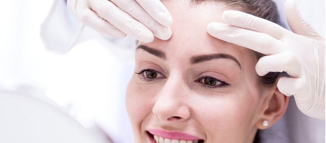 A Lady's forehead holds by doctor | Botox vs Filler | Resurgence Wellness in Arlington, TX